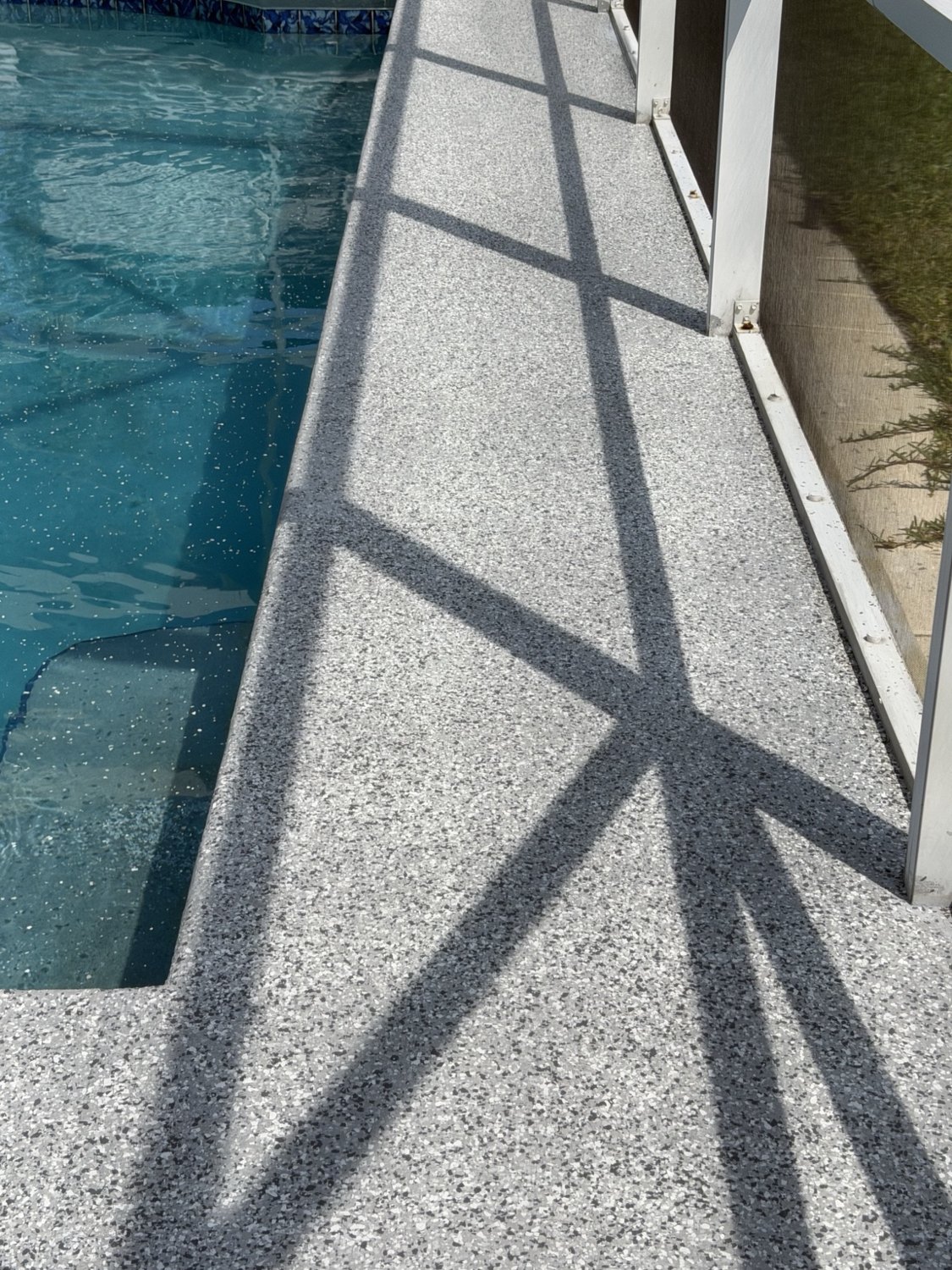 Gray finished pool deck surface alongside swimming pool