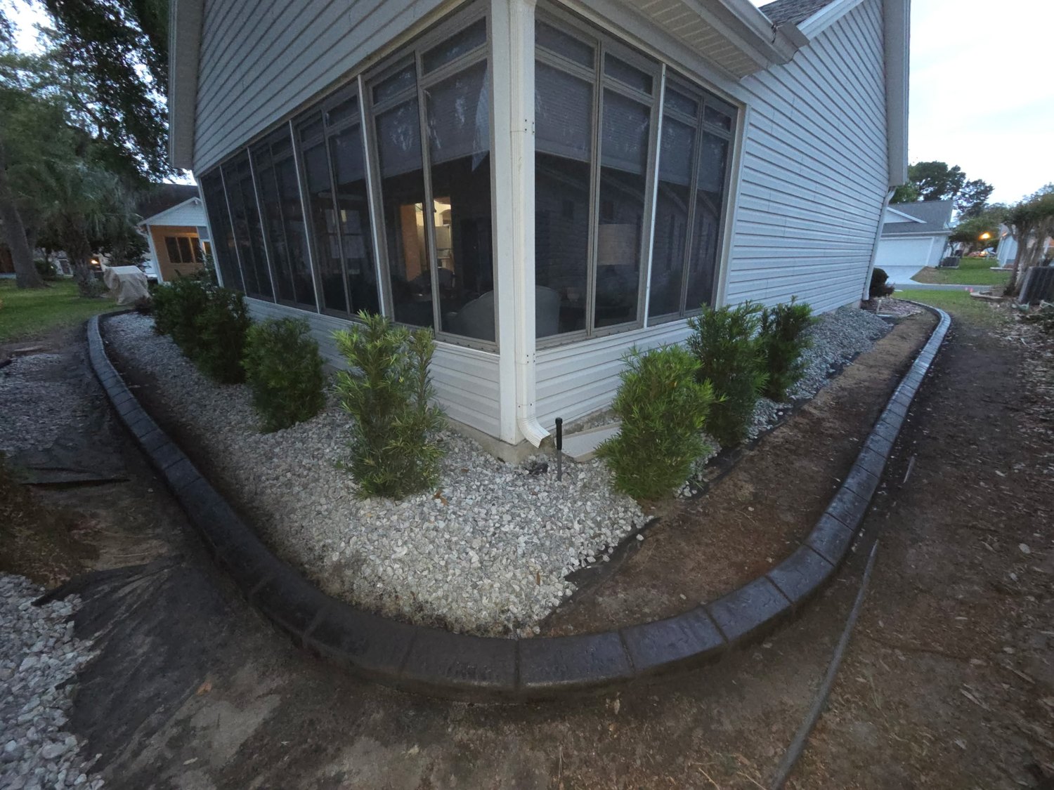 Side-yard landscape border with decorative stone and shrubs