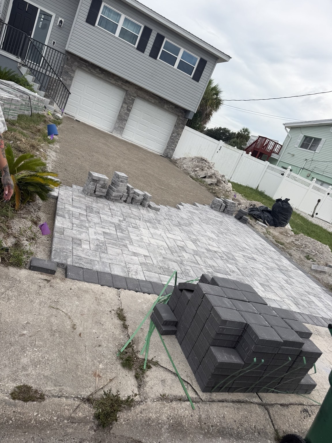 Paver driveway installation in progress with pavers and materials on site