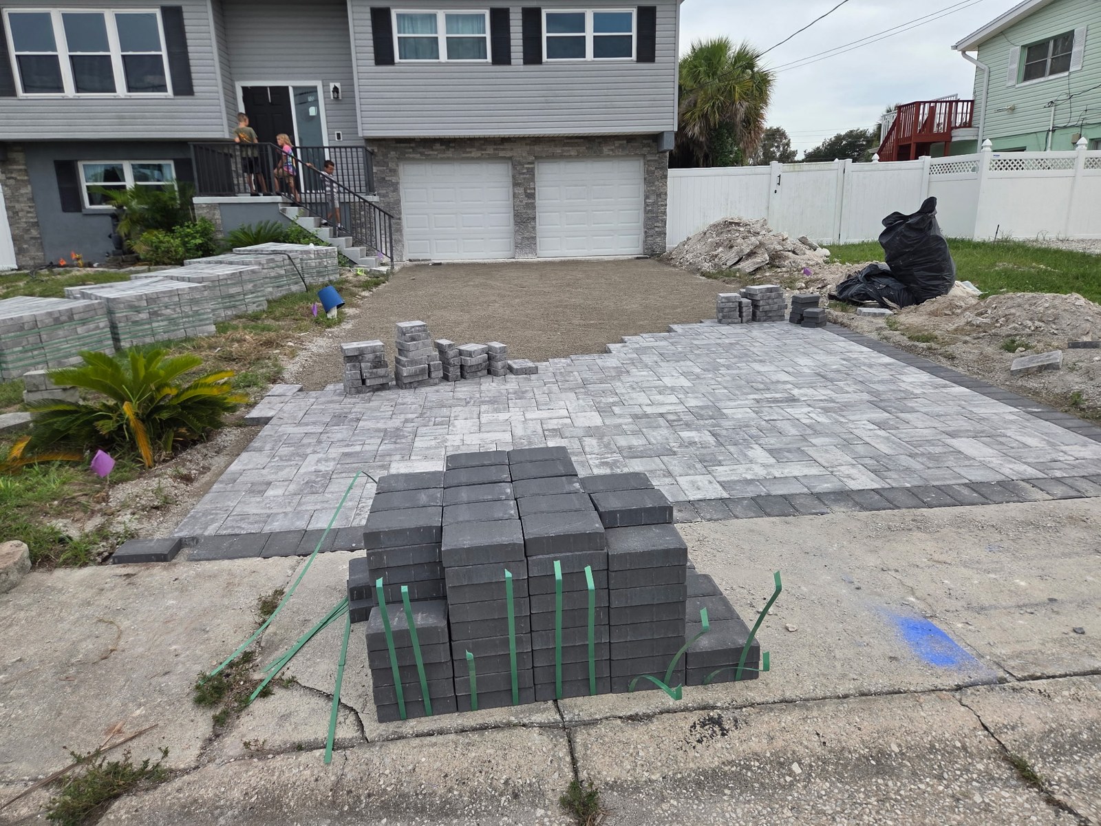 Paver driveway installation showing the patterned field and dark border