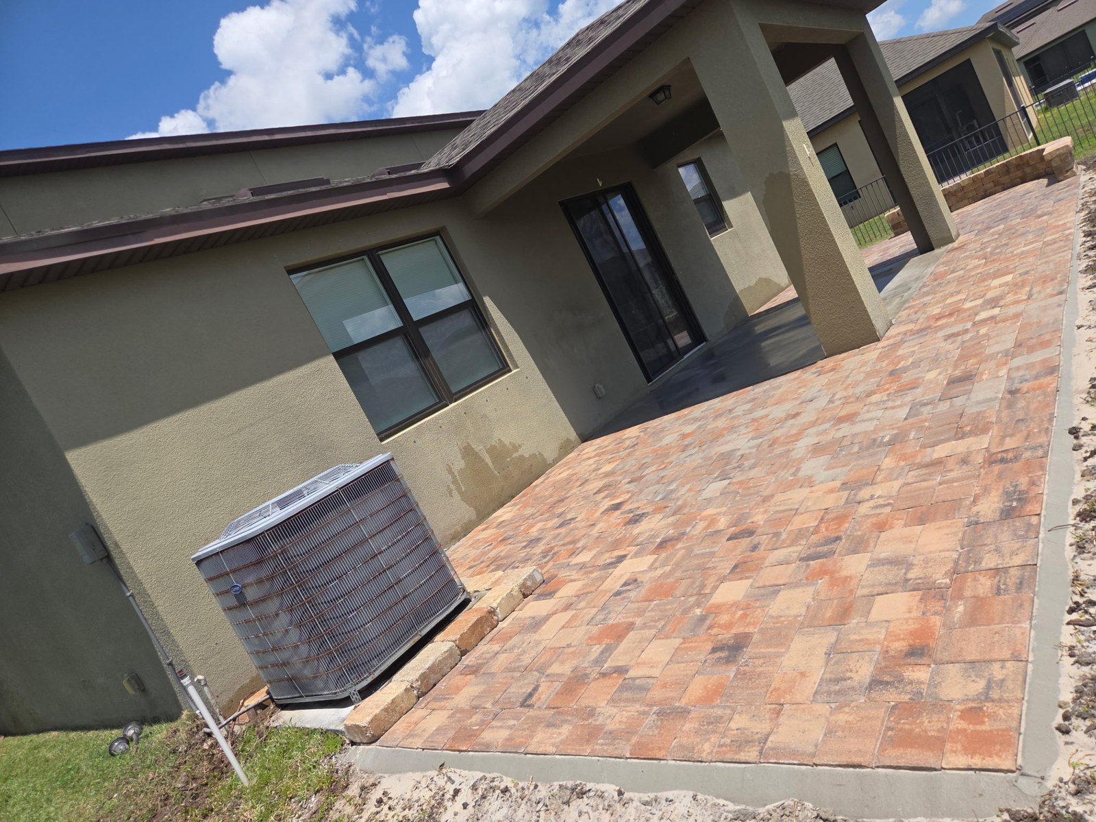 Wide view of finished paver patio along the home